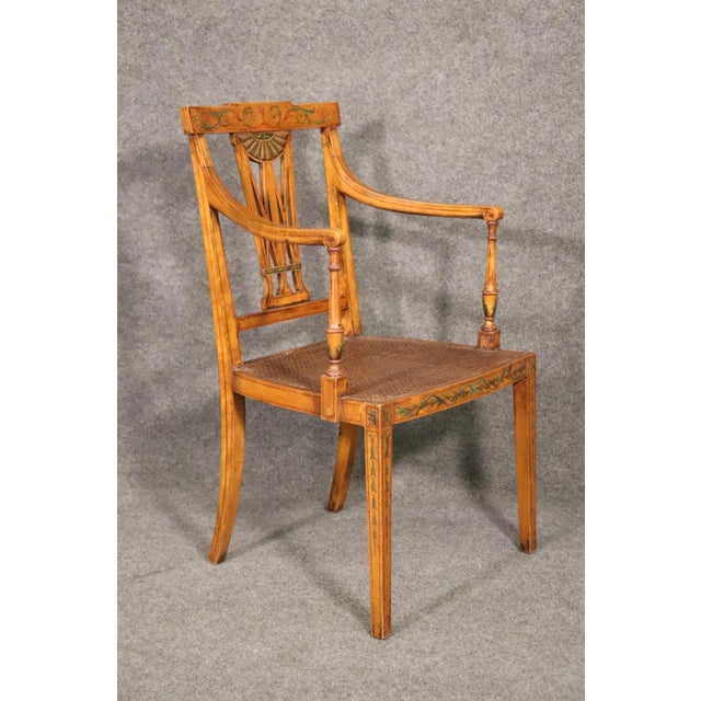 This fine quality paint decorated English satinwood Adams cane armchair, circa 1920, is a superb example of early 20th-...