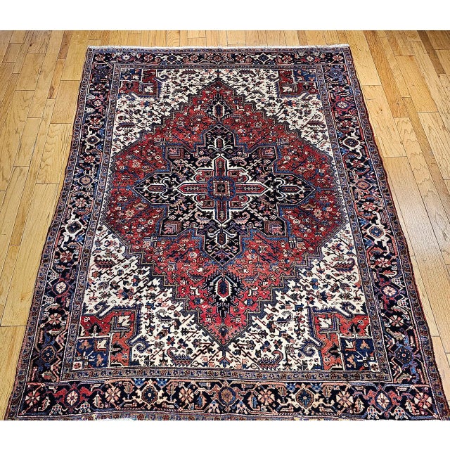 "This vintage Persian Heriz rug from the second quarter of the 20th century showcases a vibrant brick-red field anchoring...