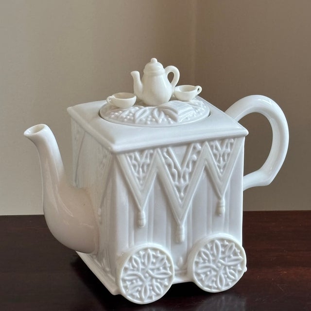 Offering a late-20th century Lenox porcelain teapot in the form of an elegant tea cart, complete with sculptural wheel...