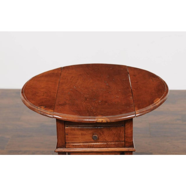 An English yew wood drop-leaf side table from the second half of the 19th century, with circular top, single drawer and...