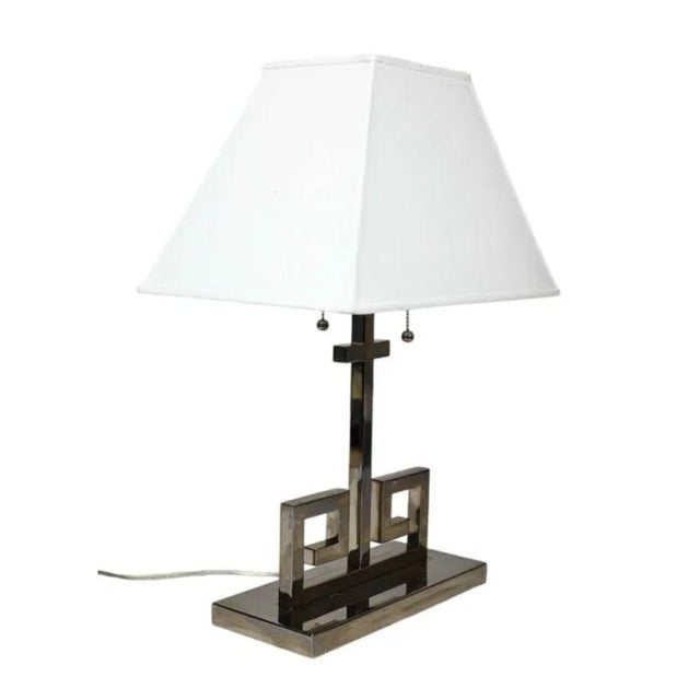 A pair of vintage Greek key chrome table lamps from Visual Comfort. Each chrome lamp shines and features a modern...