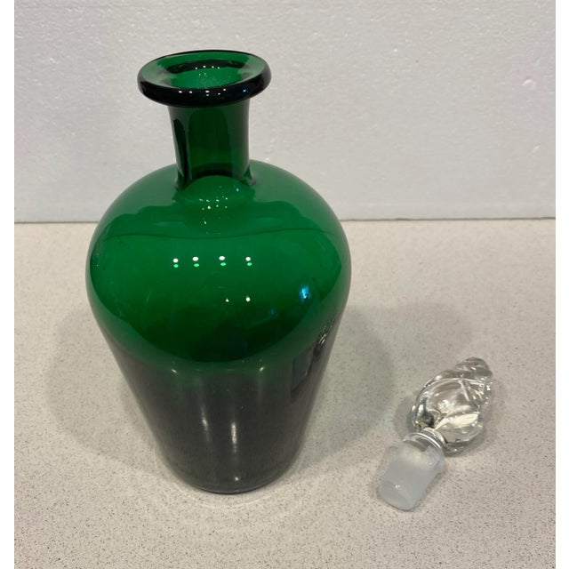 Beautiful emerald green glass decanter with clear glass decorative stopper. This is a solid, heavy piece. Rare to find...