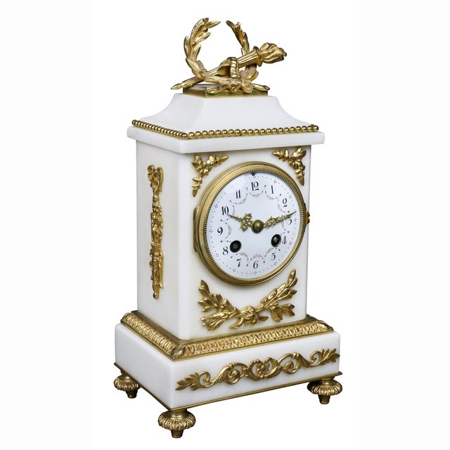 The clock with laurel wreath and torch finial over a clock set in a rectangular case, bronze feet. Together with a pair of...
