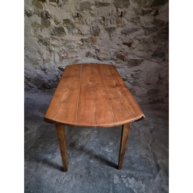 Antique French drop-leaf dining table dating from around 1900. The table has a cherrywood top and beech legs, with a...
