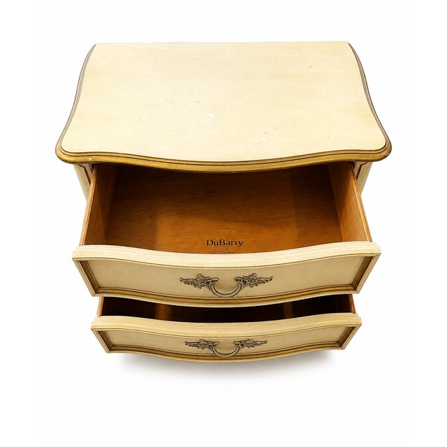 This is a vintage French Provincial style two-drawer nightstand or bedside table from the Bonnet series manufactured and...
