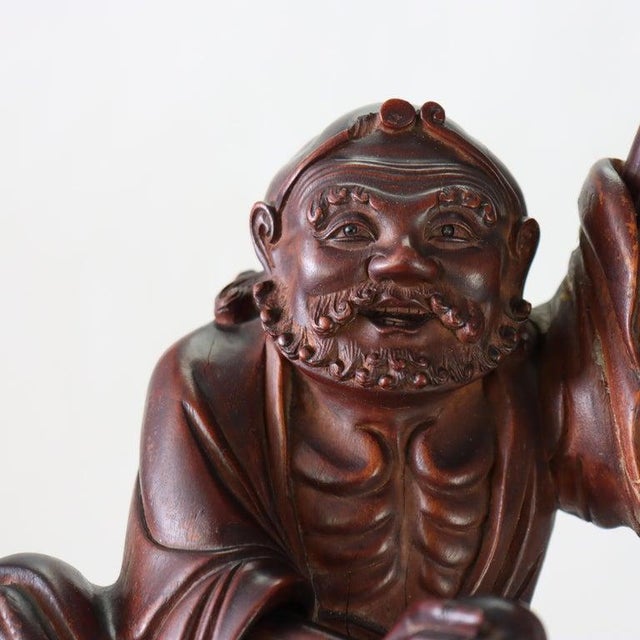 A 19th Century Chinese carved wood folklore figure, presented on a natural root wood base. This finely rendered sculpture,...