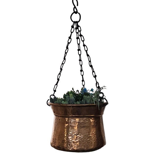 Authentic mid-century hand-hammered copper hanging planter featuring a substantial handcrafted body suspended from its...
