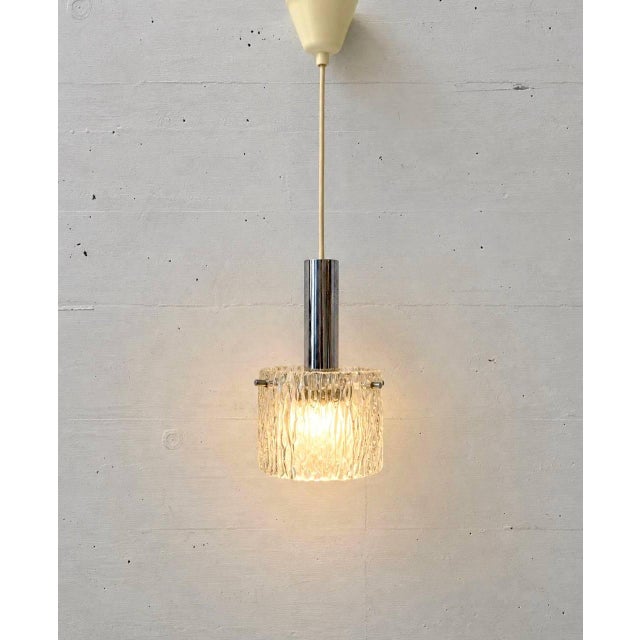 A distinctive german vintage pendant lamp from the 1970s. the lamp features a cylindrical shade made of solid, clear...