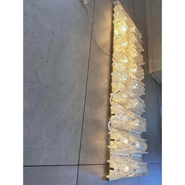 Huge rectangular wall sconce in unlaquered brass and transparent murano glass with a partcular shape that give brigtness ....