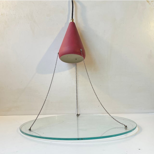 Unusual Stilnovo inspired pendant lamp in Brass, Glass and Aluminum. It's fashioned from a maroon colored shade beneath...