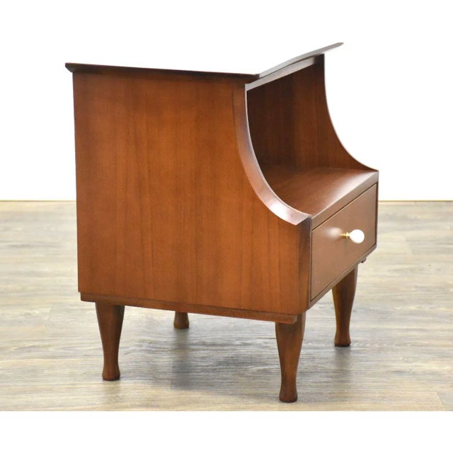 A mid century modern walnut nightstand that has a similar white porcelain knob to the designs of Kipp Stewart and Stewart...