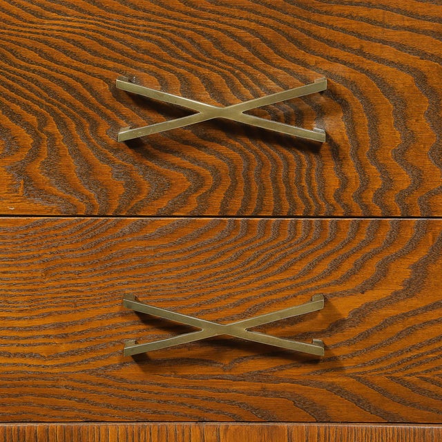 This stately Mid-Century Paul Frankl perused Oak Chest of Drawers w/ Legs & X-Form Brass Pulls originated in the United...