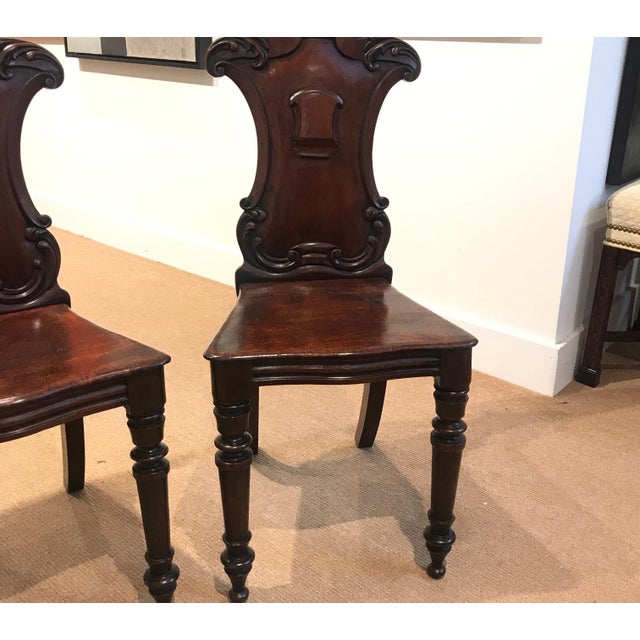 Beautifully carved mahogany hall chairs with armorial backs, hand-turned legs and solid mahogany seats. The chairs with...