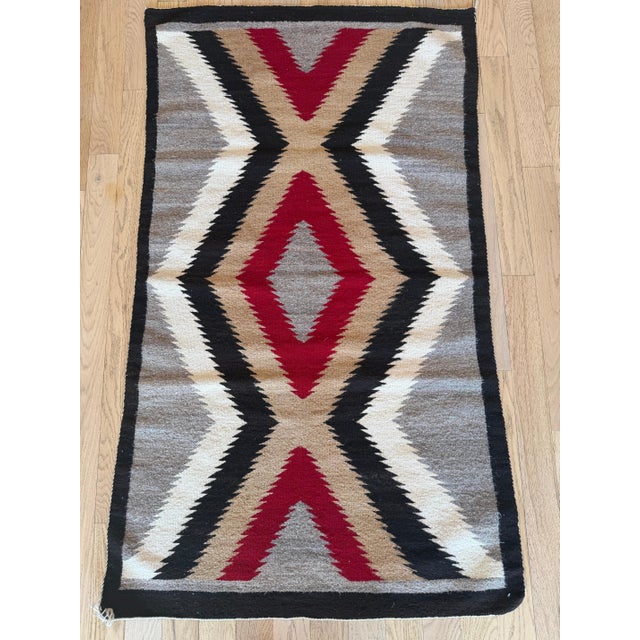 This striking mid-20th century Navajo rug is defined by a bold, rhythmic arrangement of interlocking chevrons and diamond...