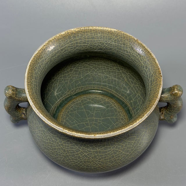 This antique Chinese Longquan celadon censer features two elegantly shaped side handles. The whole surface is covered with...