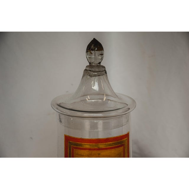 The jar maintains its original painted label in a beautiful orange and gold patina. While the jar is now empty the label...