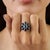 5.06 ct. of blue sapphires are arranged in a floral cluster, with nine oval-cut gemstones forming a balanced petal-like...