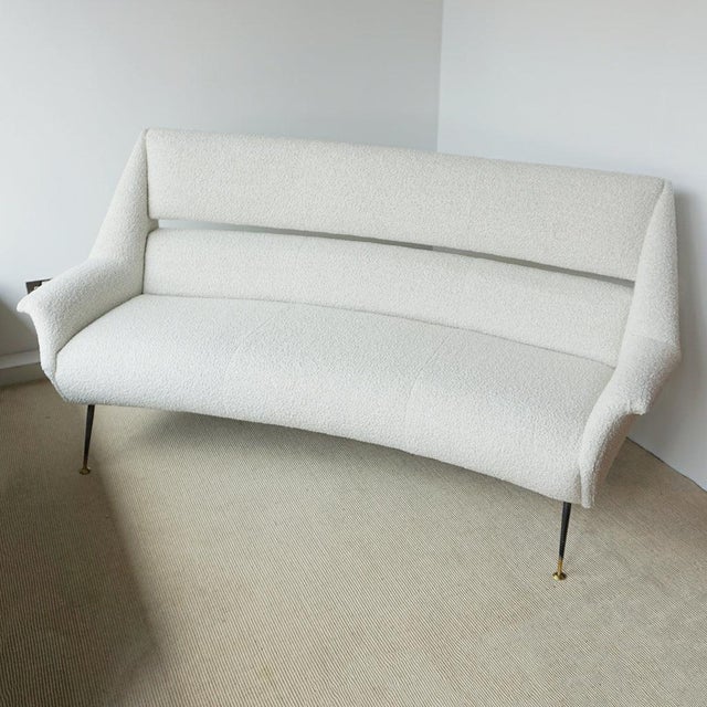 A mid-century sofa by gigi radice for minotti. Re-upholstered in white boucle with original steel and brass capped feet....
