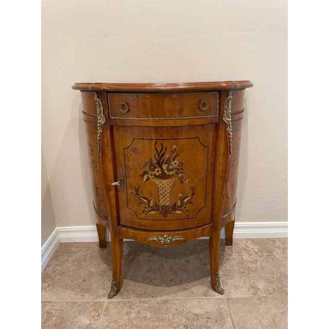 Italian neoclassical style accent cabinet. The lovely faux marquetry depicts a basket with flowers on the front of this...