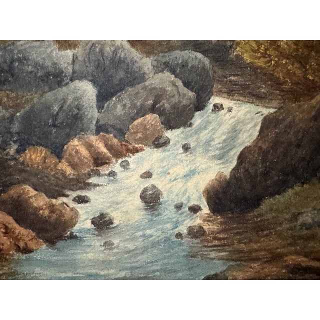Original watercolor on paper depicting a rocky mountain stream flowing through large boulders beneath a steep dark...