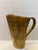 Handcrafted studio pottery ceramic pitcher featuring geometric carved decoration and earthy brown and sand-toned glaze....