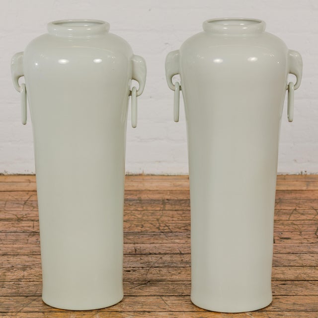 A very near pair of white porcelain tall and slender vintage altar vases with elephant handles, ring pulls and tapering...