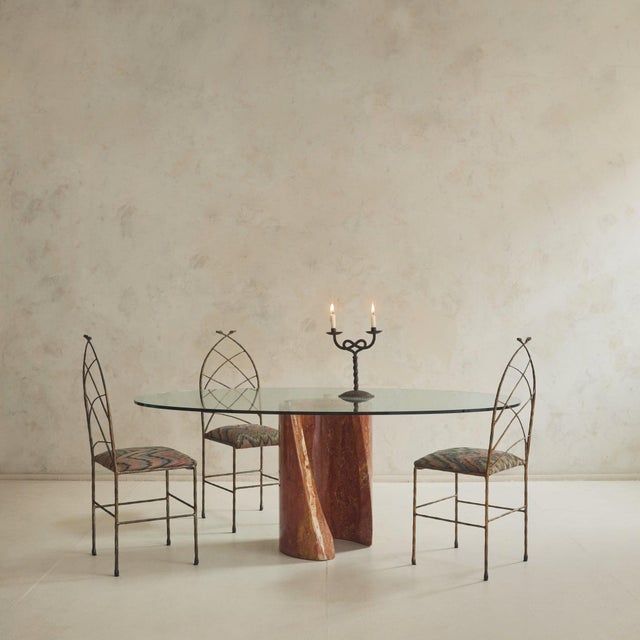 An Italian dining table from the 1970s, defined by its contrast of weight and transparency. A thick oval glass top rests...