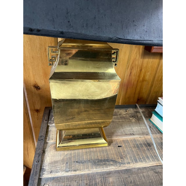 This Hollywood Regency style table lamp features a polished brass base with distinctive geometric handles and a bell-...