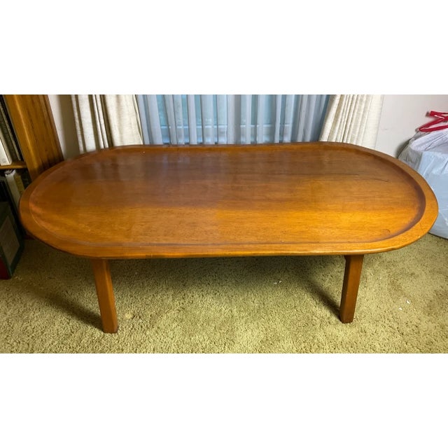 This elegant Scandinavian Modern teak coffee table features the classic "surfboard" oblong shape that defined mid-century...