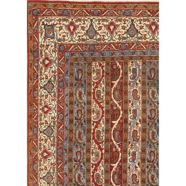 A pristine ivory field across the body of this Antique Persian rug sports a lavish decoration of interlinked blossoms....