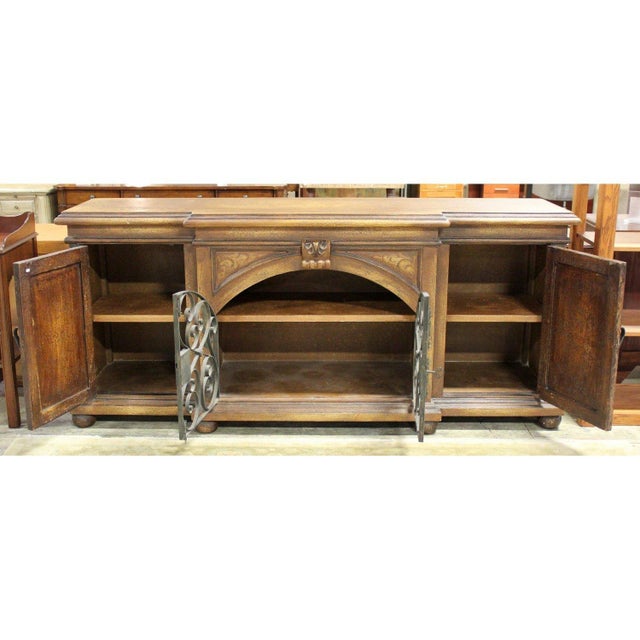 This piece features a distressed wood finish with metal corner brackets and decorative hardware that emphasize its rustic...