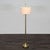 This elegant floor lamp features a sturdy brass base and pole, topped with a simple white fabric drum shade. It includes...