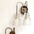This pair of wall lamps is reminiscent of the designs by Angelo Ostuni. It features glass diffusers. European Plug (up to...