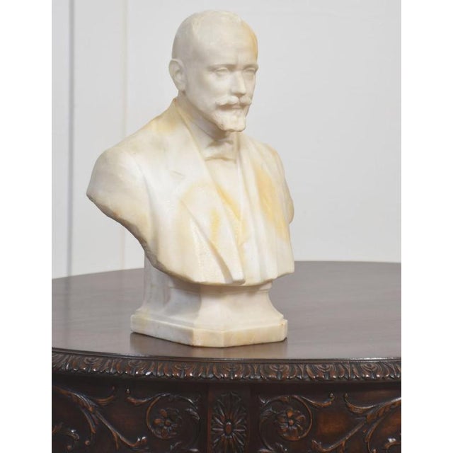 Carved marble portrait bust depicting a formally dressed gentleman with closely cropped hair, prominent moustache, and...