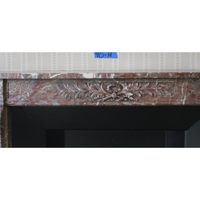This antique Louis XVI style marble fireplace mantle is carved from burgundy marble with striking gray and white veining...