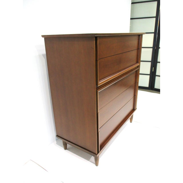 A very well-crafted Mid-Century walnut five drawer highboy dresser chest with unique built in pulls that follow the...