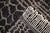 A striking lattice of honeycomb and grid lines emerges in taupe against deep charcoal, giving this rug the graphic energy...