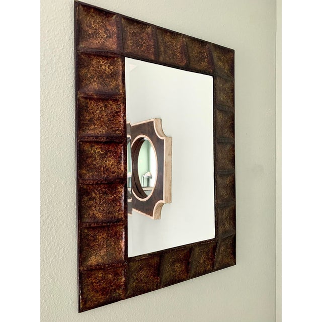 Description: Sculptural wall mirror featuring a striking hammered metal frame with a rich copper and bronze patina. The...