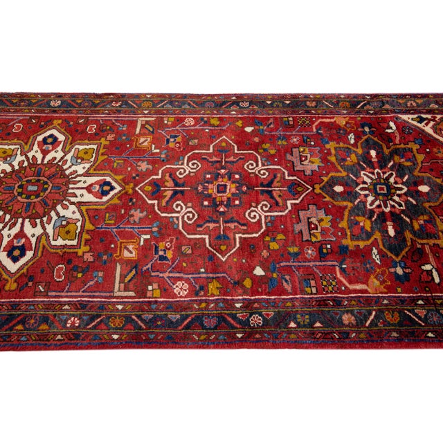 Beautiful vintage Persian Heriz hand-knotted wool runner with a red field. This Persian rug has a blue frame and...