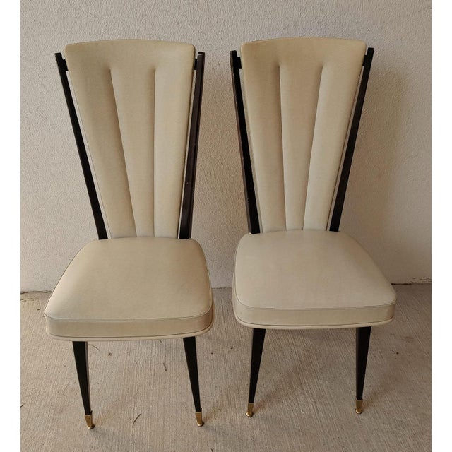 Vintage 1960s dining chairs in beige faux leather, with a mahogany-stained wood frame and copper protective caps on the...