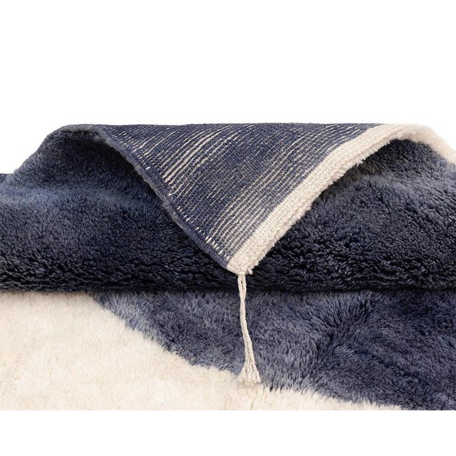 This hand-knotted wool rug reads like a modern art composition — softly rounded, organic forms in sunlit sienna, deep...
