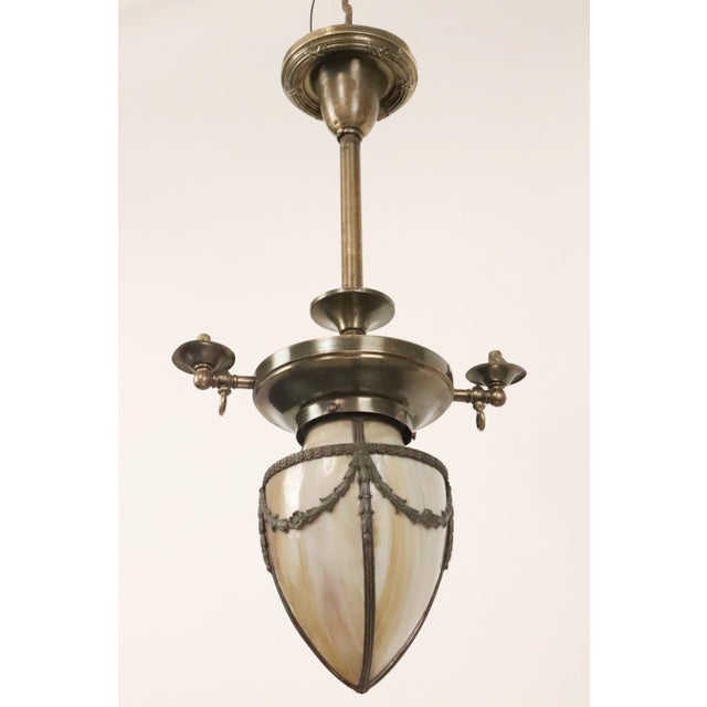 This converted gas chandelier now turned pendant light features ornate floral and steel swag detail with a beige stained...