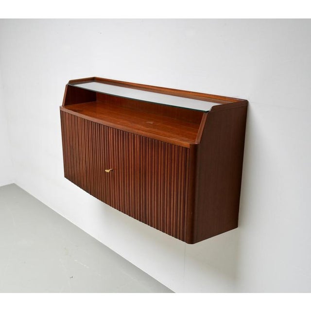 Paolo Buffa wall-mounted credenza, Italy, 1950s. This compact cabinet is executed with a vertically ribbed front, rounded...