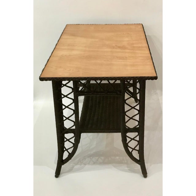 Dark brown painted wicker base with blond wood writing surface Braided wicker accent surrounds the top Woven wicker shelf...