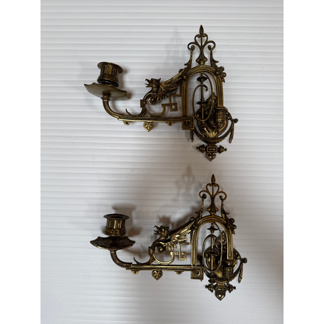 Design Plus Gallery presents a Pair of Antique Piano Sconces of Brass. This pair of reticulating armed sconces has a...
