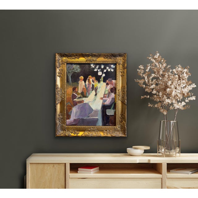 A beautiful framed figurative print on canvas depicting a summer night dinner party under the warm glow of stringing lights .