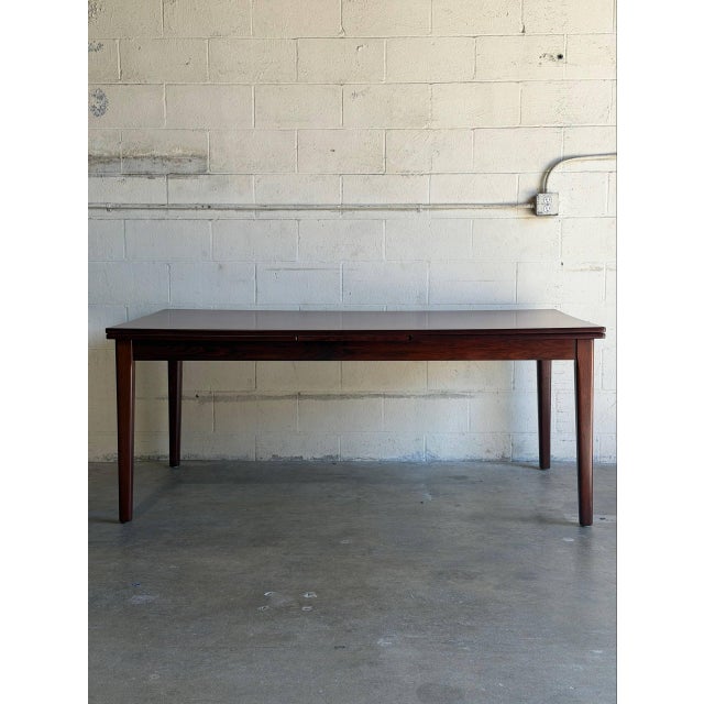 This large dining table features a sleek rectangular top bordered by refined solid edges. The versatile frame incorporates...