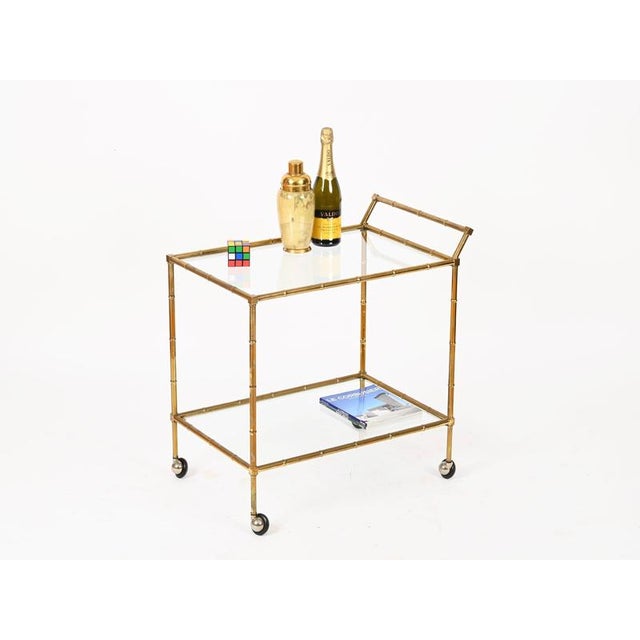Gorgeous and unique Mid-Century bar cart entirely crafted in faux-bamboo solid brass and completed with crystal shelves....
