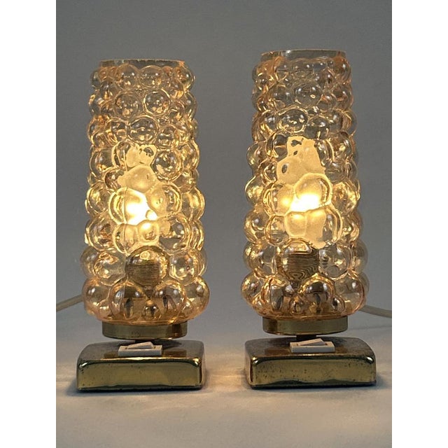 Set of two lovely and highly decorative mid-century modern brass and bubble glass bedside table lamps. Designed and...