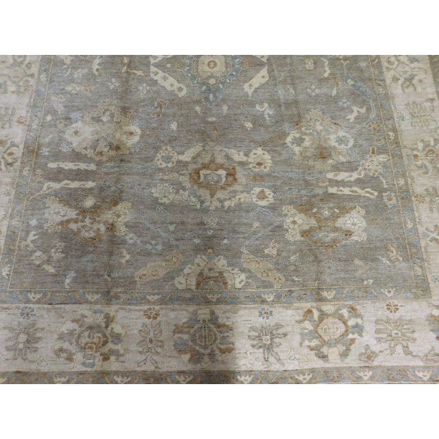 Soft grey field decorated with soft flowing motifs within ivory border.